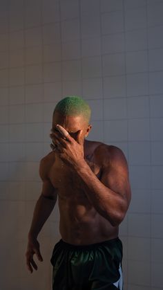 a shirtless man with green hair and no shirt standing in front of a white tiled wall