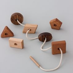 several wooden toys are tied together on a gray surface with white string and wood pegs