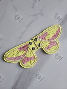 a yellow and pink moth on a marble surface