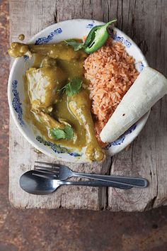 a white plate topped with rice and green curry next to a burrito covered in sauce