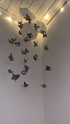 a group of butterflies hanging from the ceiling in a room with white walls and lights