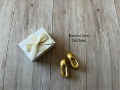 a present box and pair of gold baby shoes on wooden floor with text overlay