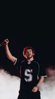 a man with red hair holding a baseball bat in his right hand and wearing a black uniform