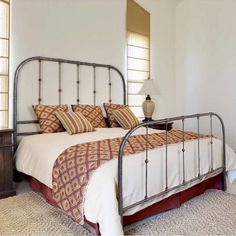 a bedroom with a metal bed frame and pillows on top of the bedspread