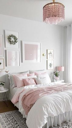 a white bedroom with pink accents and pictures on the wall above the bed, along with a chandelier