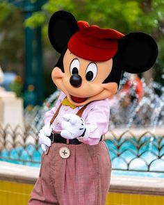 the mickey mouse mascot is standing in front of a fountain