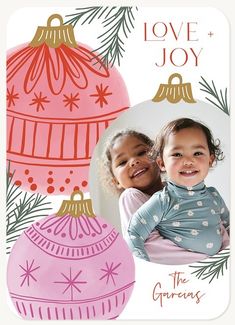 two children are smiling for the camera with christmas ornaments in front of them and an ornament