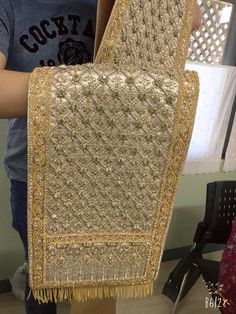 a person holding up a piece of cloth with beading and fringes on it