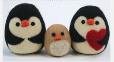 three small stuffed penguins holding a heart