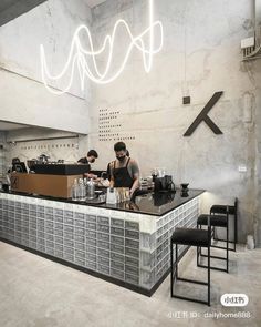 a man standing at a counter in front of a bar with chairs and lights above it