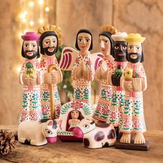 a group of wooden figurines sitting on top of a table next to a pine cone