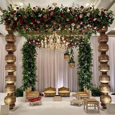 a decorated stage with flowers and chandeliers on the wall, couches and tables