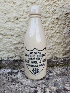 an old bottle sitting on the ground next to a wall