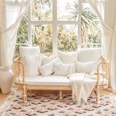 a white couch sitting under a window in a living room next to a potted plant