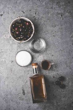 a bottle of liquor next to two glasses and a cup filled with ice cubes