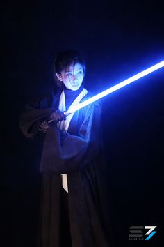 a woman holding a light saber in her hand and wearing a black outfit with blue lights