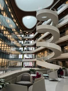 a spiral staircase in the middle of a building with lots of windows and chairs around it