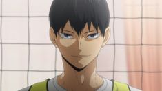 a young man with black hair and blue eyes stares at the camera while standing in front of a volleyball net