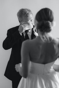 a man in a tuxedo is looking at his reflection in the mirror as he fixes his eyeglasses