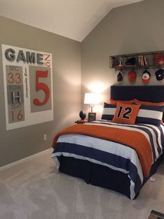 a bedroom decorated in orange, blue and white with sports themed decor on the walls