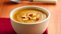 a white bowl filled with soup sitting on top of a red napkin next to a spoon