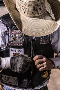 a man wearing a cowboy hat and leather vest with patches on the side, holding his hand in his pocket