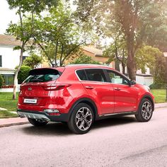 a red car is parked on the side of the road in front of a house