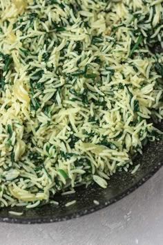 a pan filled with rice and spinach on top of a table