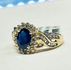 a ring with a blue stone surrounded by white and clear stones on a counter top