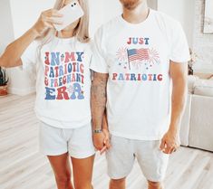 a man and woman standing next to each other in front of a white wall with an american flag on it