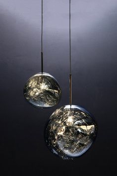 two glass balls hanging from the ceiling in a dark room with light coming through them