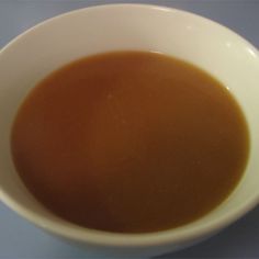 a white bowl filled with brown liquid on top of a table