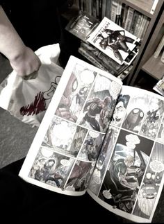 a person holding an open comic book in their hand