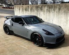 a silver sports car parked in front of a concrete wall