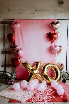 an image of balloon decorations and balloons on the floor in front of a pink backdrop