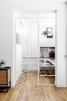 an office with white walls and wood flooring is seen through the glass partitions