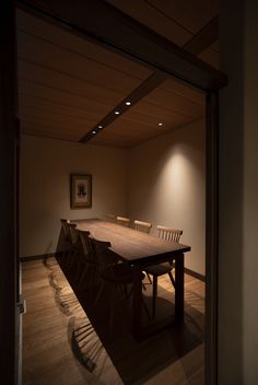 an empty room with a long table and chairs in it, lit by two lights