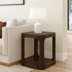 a white couch sitting next to a wooden table on top of a hard wood floor