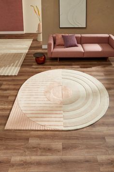 a modern living room with wood floors and pink furniture in the center, along with a circular rug on the floor