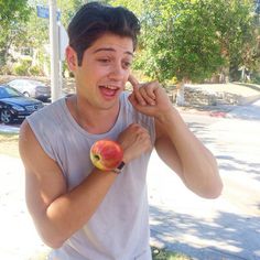 a young man holding an apple and pointing to it