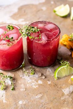 two glasses filled with red liquid and garnished with herbs