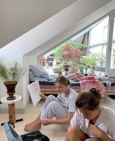 two women sitting on the floor looking at papers