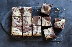 some brownies are cut into squares and sitting on a slate platter with chocolate chips