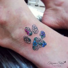 a small foot tattoo with flowers and swirls on the top of it's toe