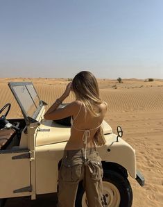 a woman is standing in the desert with her laptop on top of a vehicle and listening to music