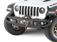 the front end of a white jeep with black bumper guards and red lettering on it