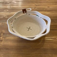 a white rope basket sitting on top of a wooden table