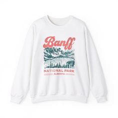 Vintage crew neck cozy fall lounge wear featuring a design of Banff National Park Moraine Lake. This medium-heavy blend of cotton and polyester sweatshirt provides a comfy wearing experience with a clean-cut style. Perfect for those colder months, it is ideal for lounging at home or going on casual outings. Relevant for nature lovers, outdoor enthusiasts, and those who enjoy cozy autumn vibes. Great for fall season, national park enthusiasts, and outdoor adventures. Product features - Cozy and comfy medium-heavy fabric blend - Elastic ribbed knit collar for shape retention - Durable double-needle stitching - Ethically grown US cotton with low environmental impact dyes - Vintage design perfect for fall and national park enthusiasts Care instructions - Machine wash: cold (max 30C or 90F) - N Winter Tshirt Designs, Fall Lounge Wear, Lac Moraine, Lake Graphic, Retro Lettering, Hiking Nature, Bold Lettering, Moraine Lake, Rugged Look