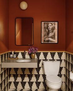 a white toilet sitting next to a sink in a bathroom under a framed picture on the wall