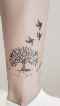 a woman's leg with a tree and birds tattoo on the bottom of it